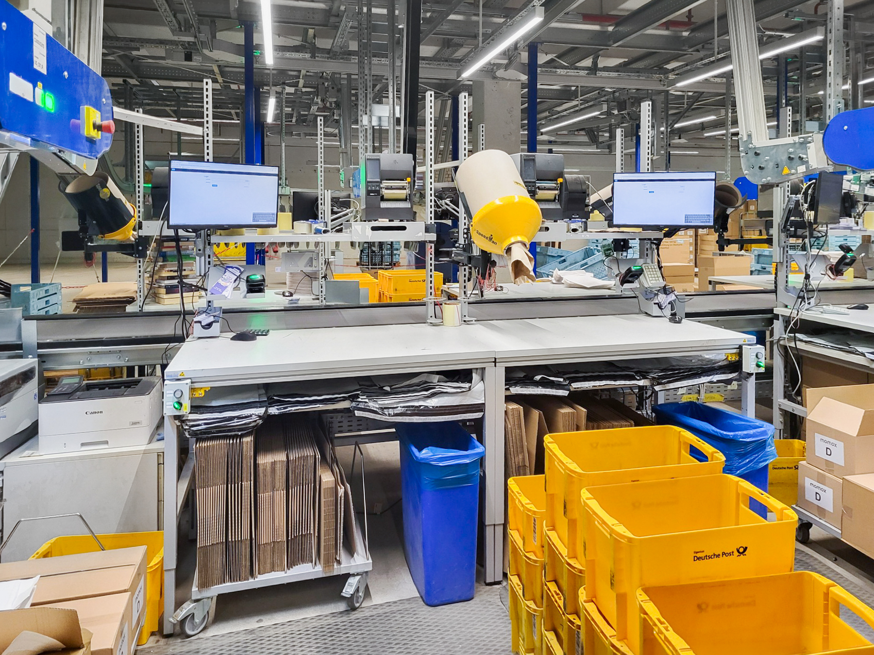 ERGO-line-Packtisch-ERGO-Basic-momox_Leipzig-004 ERGO-line Packtisch im Logistikbereich mit Monitoren, Scanner, Ablageboden, fahrbares Faltschachtelmagazin und Regalen